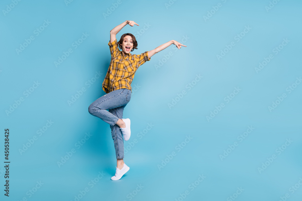 Photo of crazy funky lady indicate fingers empty space wear plaid shirt jeans shoes isolated blue color background Photo of crazy funky lady indicate fingers empty space wear plaid shirt jeans shoes isolated blue color background