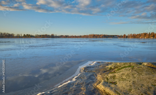 Fototapeta Naklejka Na Ścianę i Meble -  Panorama of the shores of Tuusula lake on a sunny winter day in Järvenpää: thin ice stone, sunbeams and bright sky.