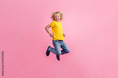 Full size profile side photo of young cheerful little boy happy positive smile jump up isolated over pink color background