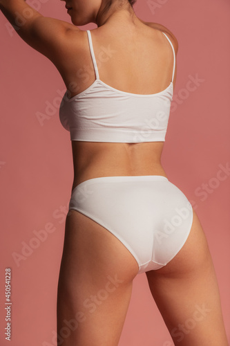 Back view of sportive body of young caucasian woman isolated on pink studio background. Natural beauty concept