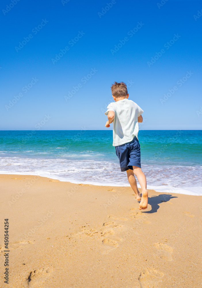 Happy boy running and playing on the summer beach. Young teenager relax and having fun in summer holiday vacation travel. High quality photo