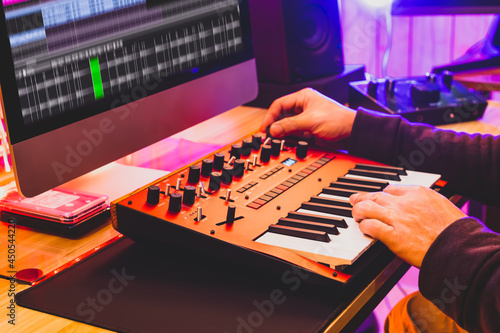 Foto professional sound designer hands playing and tweaking analog synthesizer keyboard knobs for editing sound in post production studio