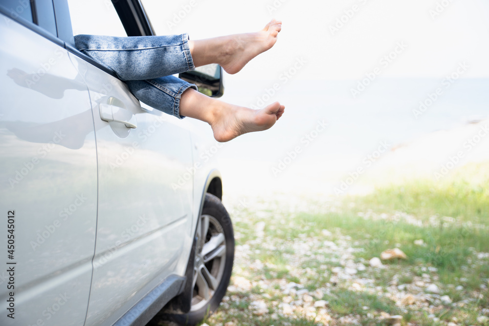 woman legs stick out from car window sea beach on background