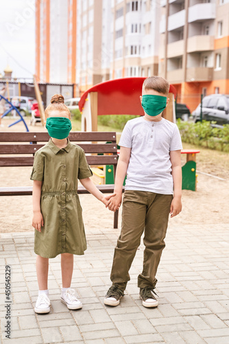 Children in safety mask. New normal. Corona virus safety portrait. Boy and girl. Family. Playground background. Outdoors. Health care