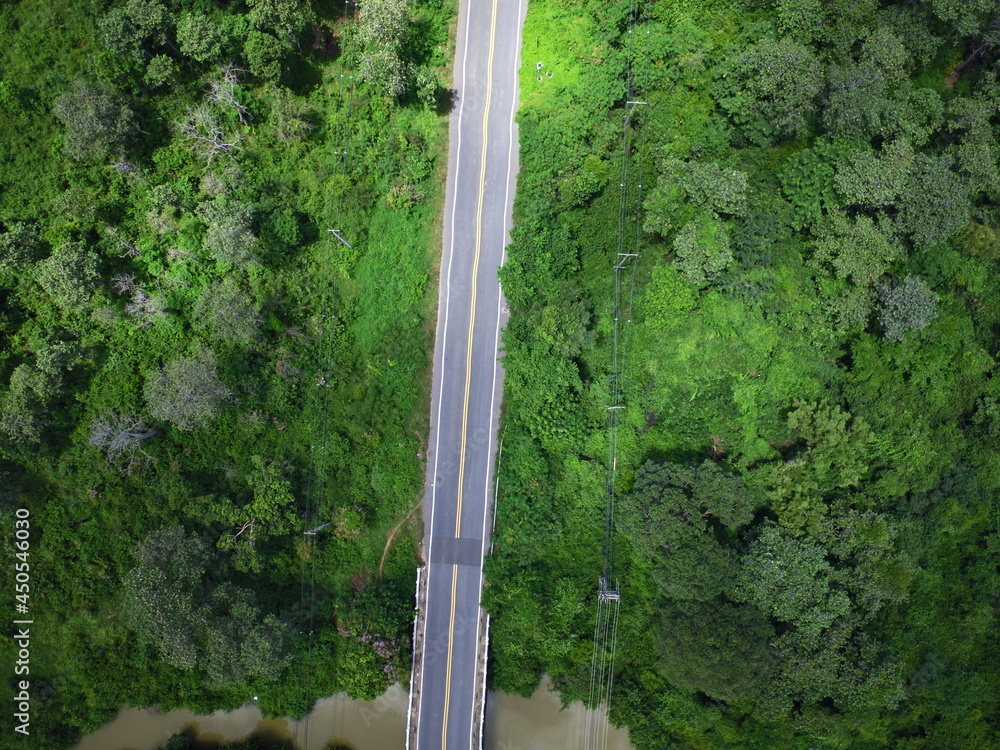 Aerial drone view of country road between green forest 