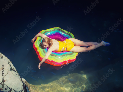 A girl in a yellow swimsuit rides in a pond among the canyons on a bright inflatable ring photo