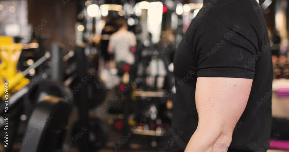 Close-up of athletic man doing biceps exercises in the gym with dumbbells. Side view. The concept of sports and active lifestyle. Close-up of athletic man doing biceps exercises in the gym with dumbbells. Side view. The concept of sports and active lifestyle.