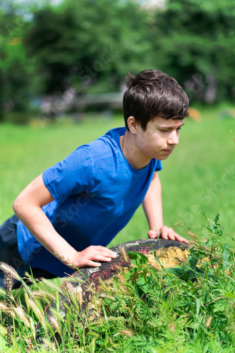 teenage boy exercising outdoors, sports ground in the yard, he does push-ups on the green grass field, healthy lifestyle