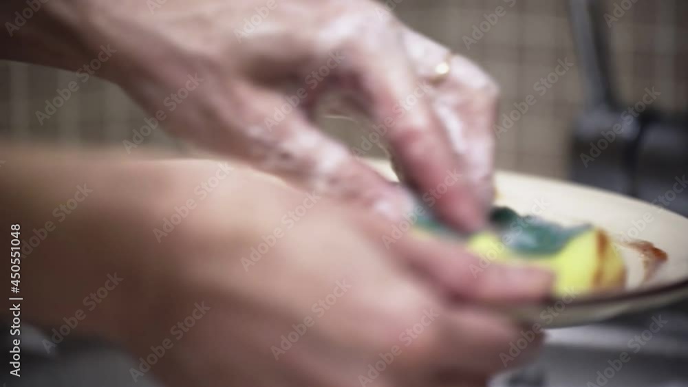 Washing dishes in the sink with detergent and a sponge in the kitchen Washing dishes in the sink with detergent and a sponge in the kitchen