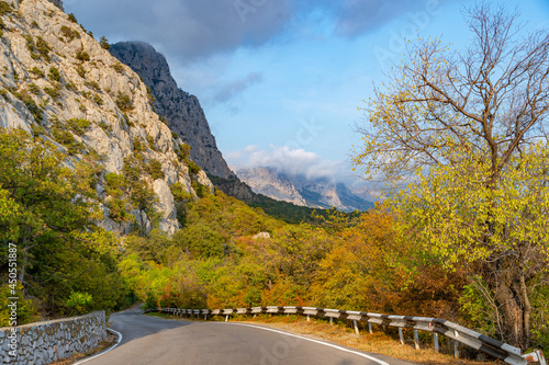 Landscape with rocks and mountains, Sunny sky with clouds and a beautiful mountain road with asphalt at sunset in autumn. Travel reference information. Highway in the mountains.Transport.