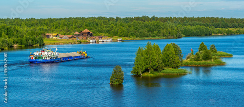 Panorama of the natural landscape of the "Russian North" A cargo ship - a large barge sails along the river, transports loose granite crushed stone and sand. Logistics and transportation.