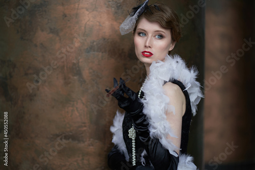 Foto A young beautiful woman in a historical costume of the 20s or 30s of the XX century with a boa and a mouthpiece