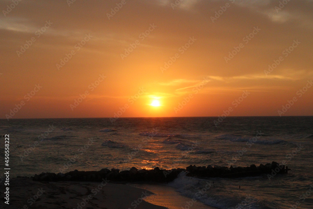Fototapeta premium Atardecer en la playa puesta de sol en el mar con cielo naranja