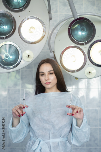 beautiful brunette in the operating room, a doctor in a surgical suit against the background of spotlights