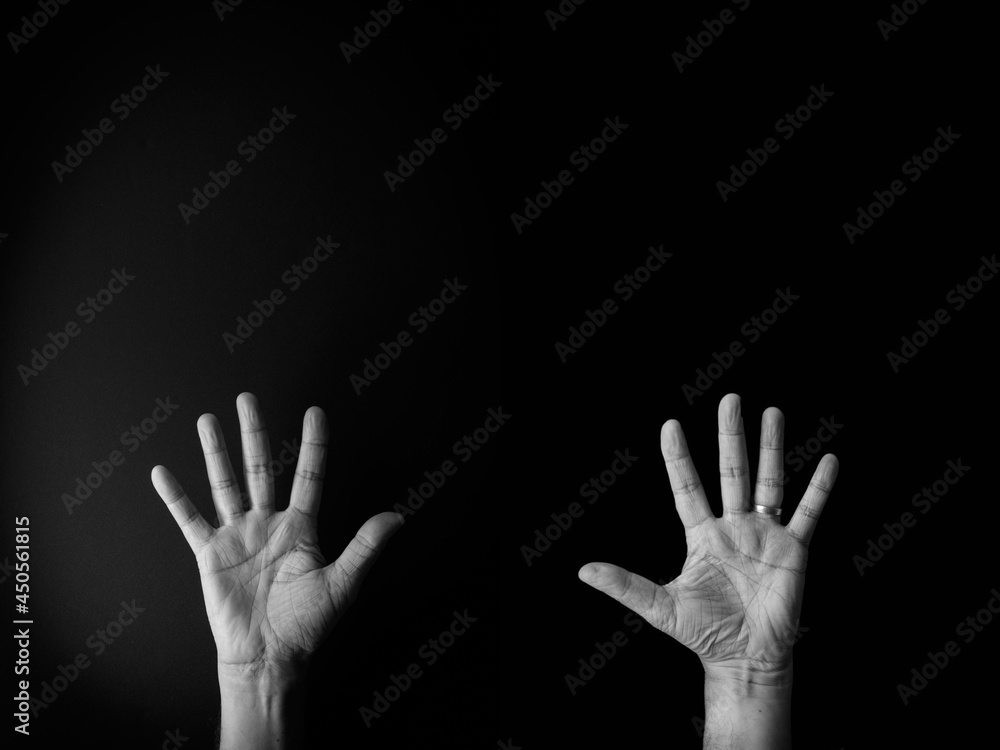 Black and white image of hand demonstrating sign language number ten against black background with empty copy space