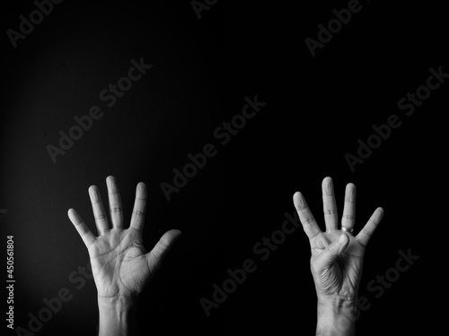 Black and white image of hand demonstrating sign language number nine against black background with empty copy space