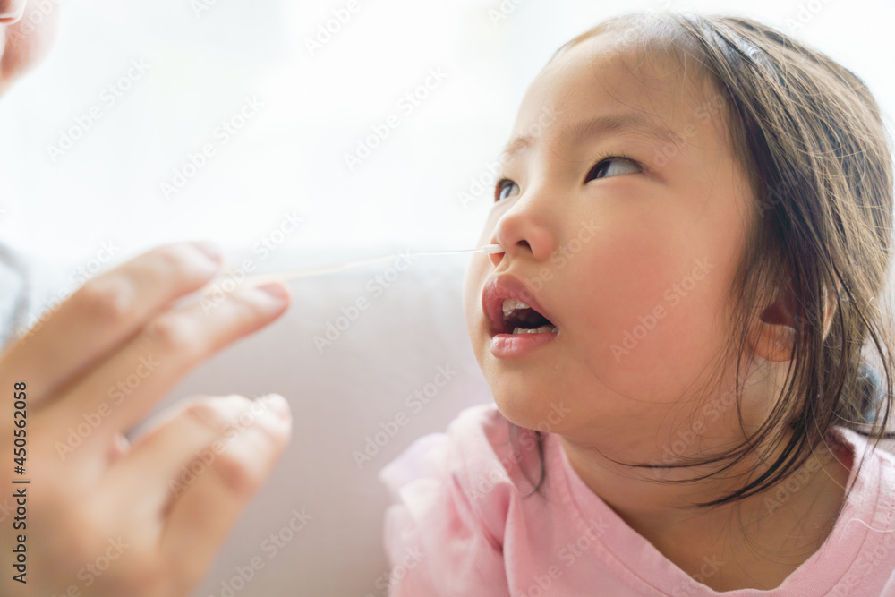 Adorable Asian girl kid getting swab test at home by her parent. Rapid self test for covid-19, Antigen test kit, quick check before school. new normal routine for kid. Selective focused. Adorable Asian girl kid getting swab test at home by her parent. Rapid self test for covid-19, Antigen test kit, quick check before school. new normal routine for kid. Selective focused.