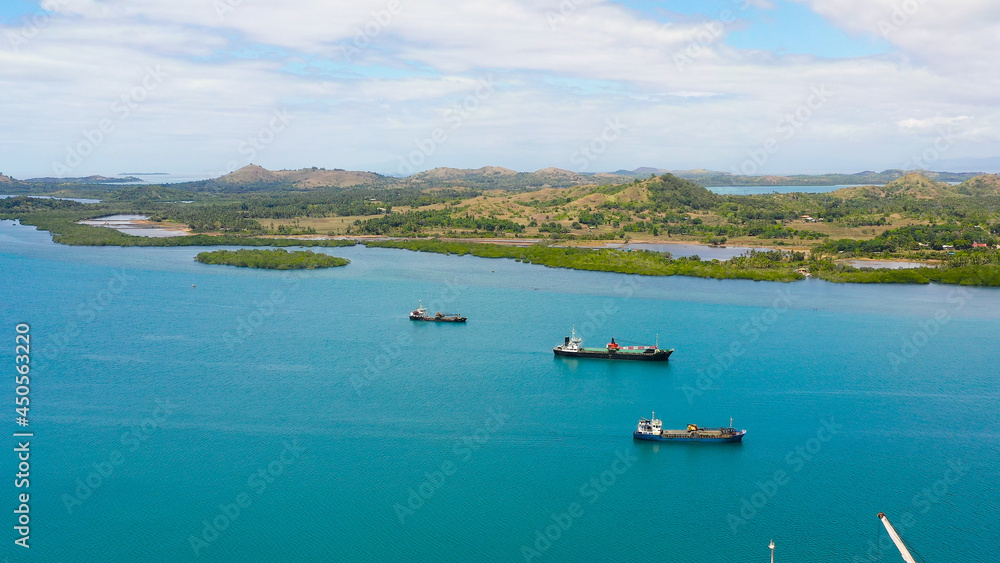 Aerial view of cargo ships leaving sea harbour at sunny day, islands on background. Tapal Wharf, Bohol, Philippines.