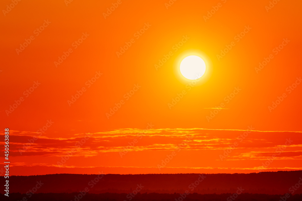 Background with bright orange light from the setting sun over the horizon. Sunset