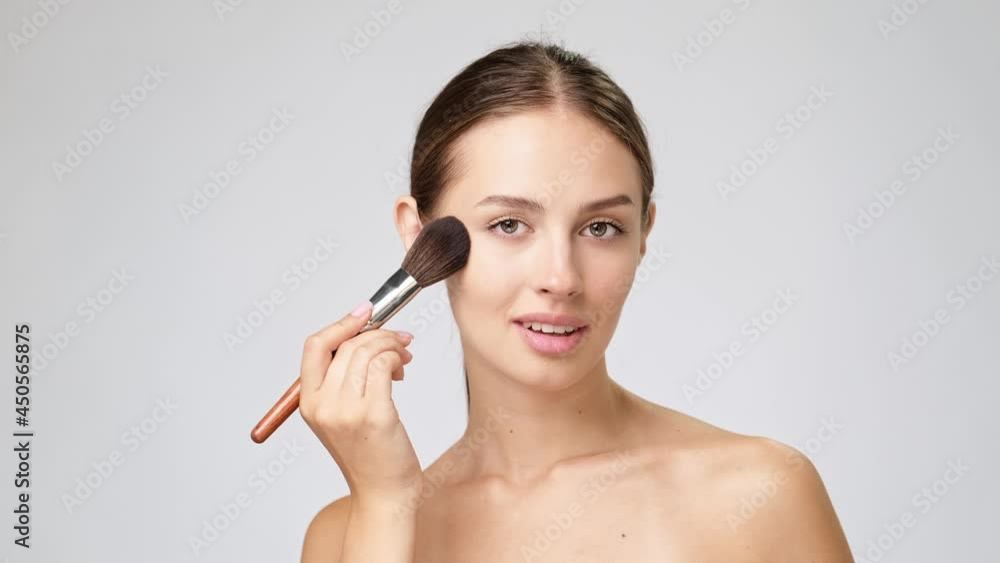 Beautiful Young Woman with Clean Fresh Skin standing over light grey background Beautiful Young Woman with Clean Fresh Skin standing over light grey background