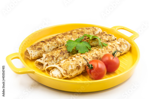 Fototapeta Naklejka Na Ścianę i Meble -  Pancakes rolls on a yellow plate with parsley and tomatoes.