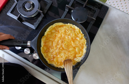 Spanish omelette cooking in a pan before turning it over