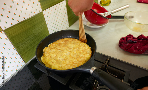 man cooking potato omelette in the pan after turning it over