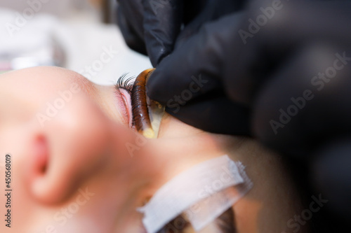 close-up of the master's hands peeling roller for curling eyelashes from the model's eyelids