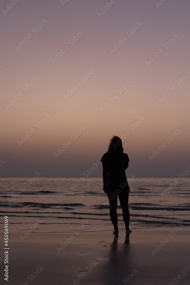 silhouette einer frau am strand bei dämmerung