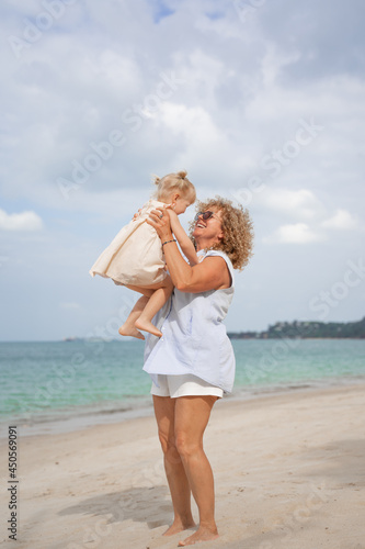 Happy girl playing with her grandmother on the beach