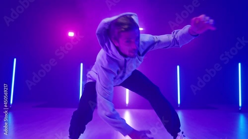 Young man breakdancing on neon lights dance floor in slow motion 4K photo