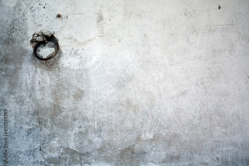 old white wall covered with dirty plaster with a visible structure. there is a ring on the wall for tying cattle or other animals photo