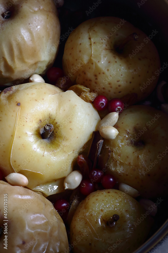 Baked apples, autumn or christmas winter dessert with cranberries, cinnamon, nuts and rosemary on dark moody background, closeup macro, from above overhead top view, healthy vegan holiday food concept Baked apples, autumn or christmas winter dessert with cranberries, cinnamon, nuts and rosemary on dark moody background, closeup macro, from above overhead top view, healthy vegan holiday food concept