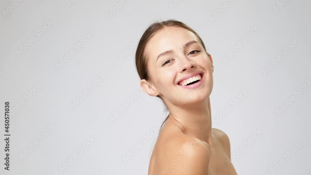 Beautiful Young Woman with Clean Fresh Skin standing over light grey background Beautiful Young Woman with Clean Fresh Skin standing over light grey background
