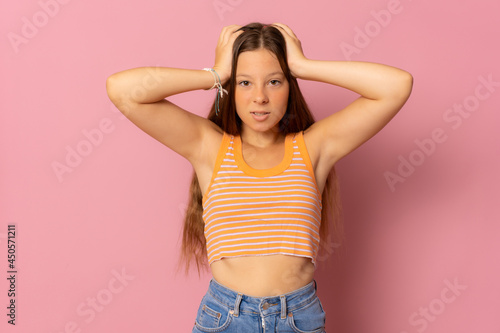 Angry teenager girl in casual clothes looking at the camera over pink background