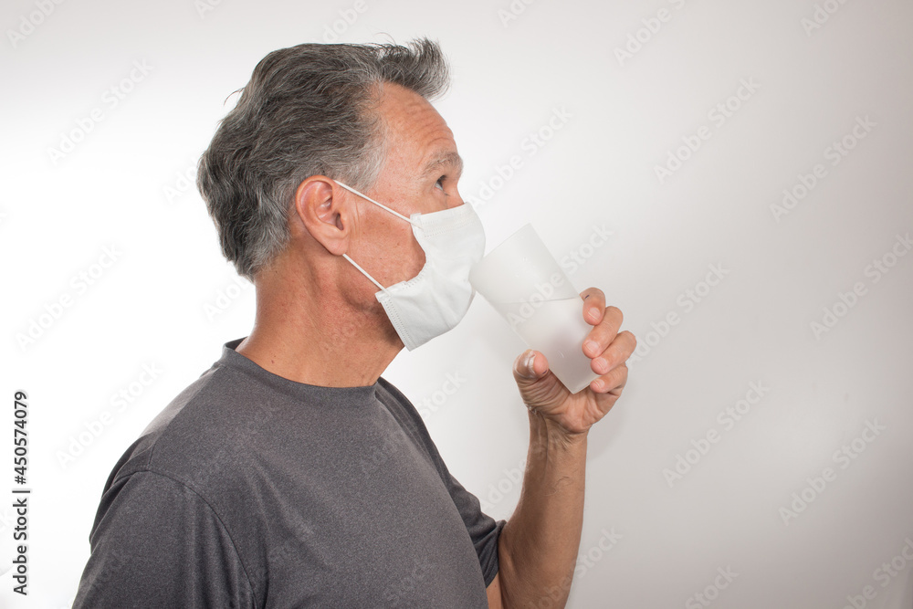 Man trying to Drink Water while still wearing his Surgical Mask Man trying to Drink Water while still wearing his Surgical Mask