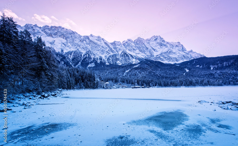 Winterlich zugefrorener Eibsee mit verschneiter Bergpanoramalandschaft im bayerischen Wettersteingebirge im morgendlichen Sonnenlicht