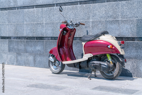 a red scooter standing against a stone wall