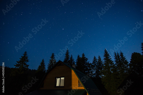 Obraz na płótnie Beautiful night landscape, house among the forest against the background of the starry sky w salonie