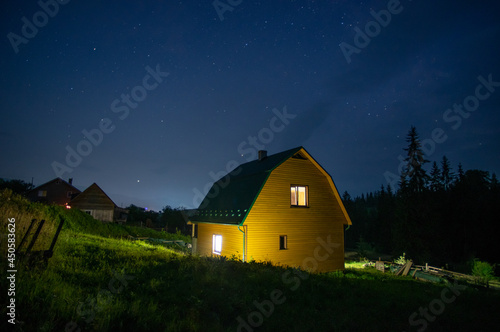 Night landscape, wooden house in a village near the forest in the mountains