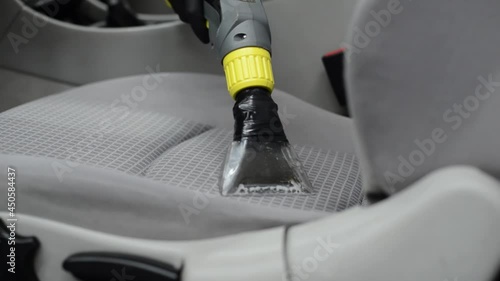 Man car detailing studio worker cleaning car textile upholstery with vacuum washer