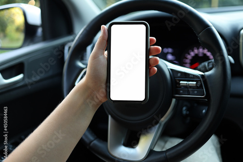 Mock up image, girl using blank white screen mobile smart phone inside a car in sunny day, touching screen or texting, copy space for your advertisement © shine.graphics
