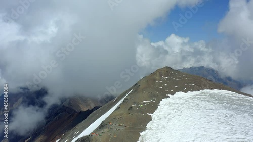 Aerial view of snow-covered mountain range, tourists tents and beautiful sky. Mountaineers' camp high in the mountains. The top of the OZhD assault camp of Mount Kazbek photo