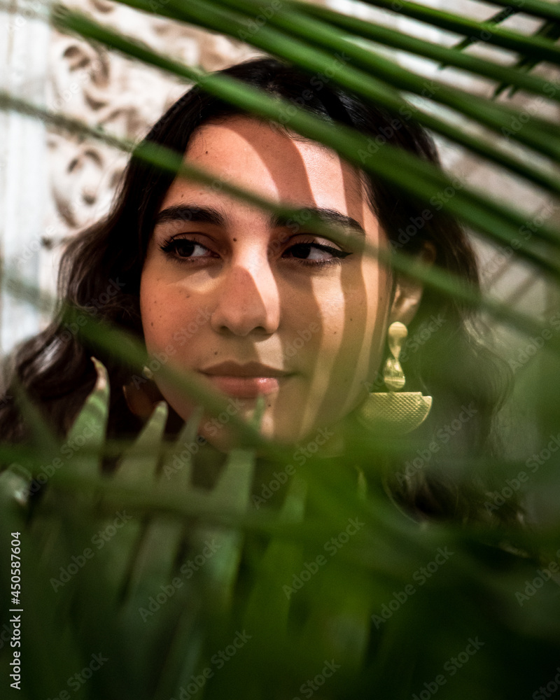Portrait of a young woman with curly hair and a pensive gaze among plants Portrait of a young woman with curly hair and a pensive gaze among plants