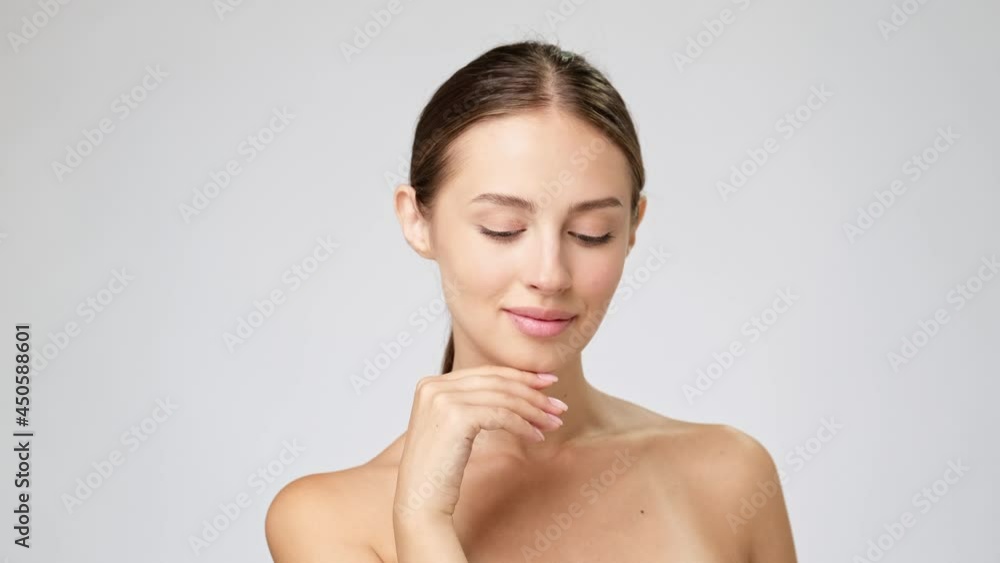 Beautiful Young Woman with Clean Fresh Skin standing over light grey background Beautiful Young Woman with Clean Fresh Skin standing over light grey background
