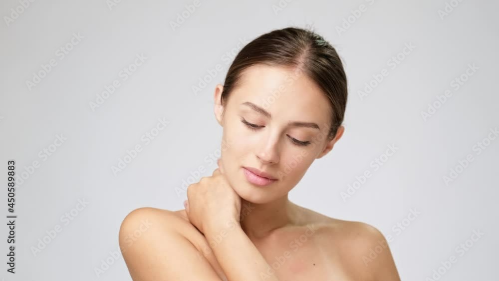 Beautiful Young Woman with Clean Fresh Skin standing over light grey background Beautiful Young Woman with Clean Fresh Skin standing over light grey background