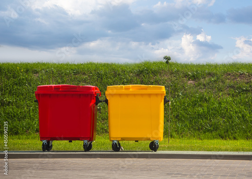 Plastic garbage containers red and yellow on the street on the lawn