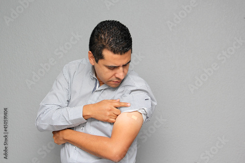 Adult Latino man showing his arm where he received the Covid-19 vaccine in the new normal  © Arlette