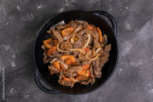 Sliced and fried filet mignon with tomato and onion in an iron skillet