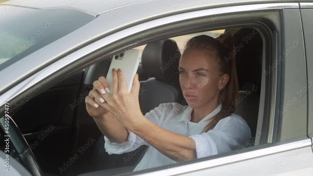 selfie while driving. the girl admires herself in the camera from the phone. selfie while driving. the girl admires herself in the camera from the phone.